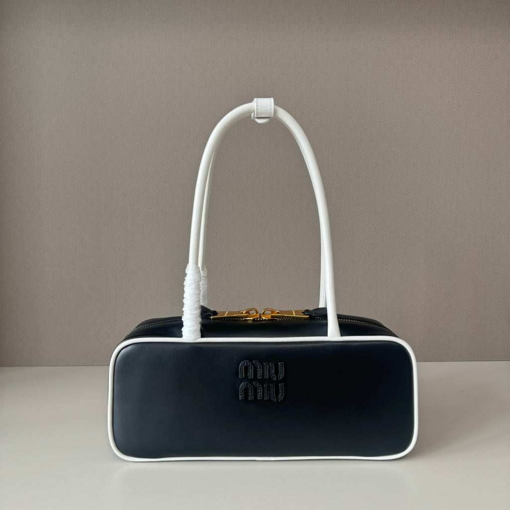 Black handbag with a white handle on a gray background