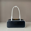 Black handbag with a white handle on a gray background