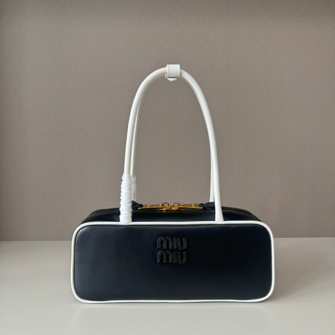 Black handbag with a white handle on a gray background